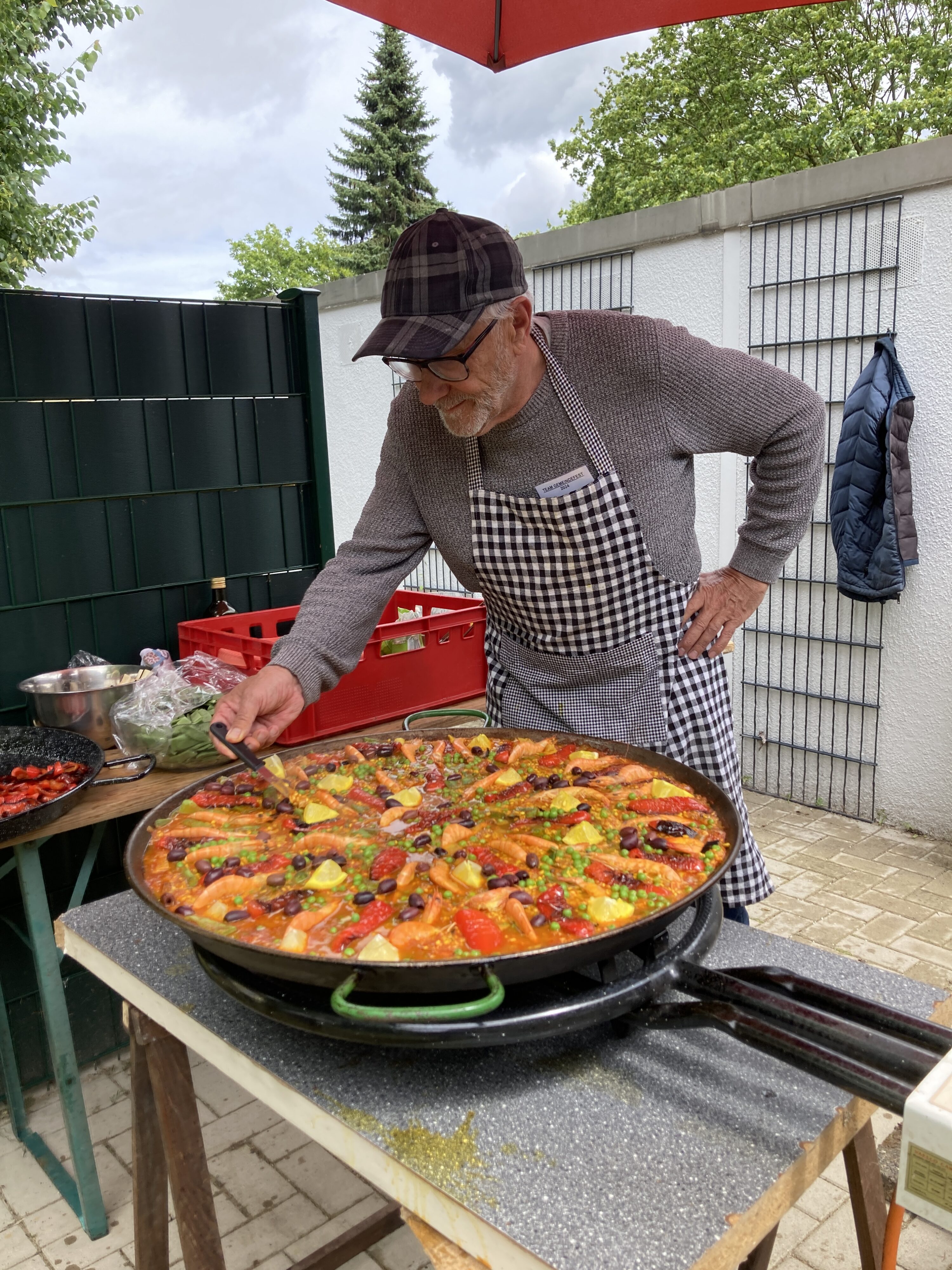 Pfarrer i.R. Heiko Dringenberg kümmert sich hingebungsvoll um eine kunstfertig zusammengestellte Paella in einer riesigen Pfanne.